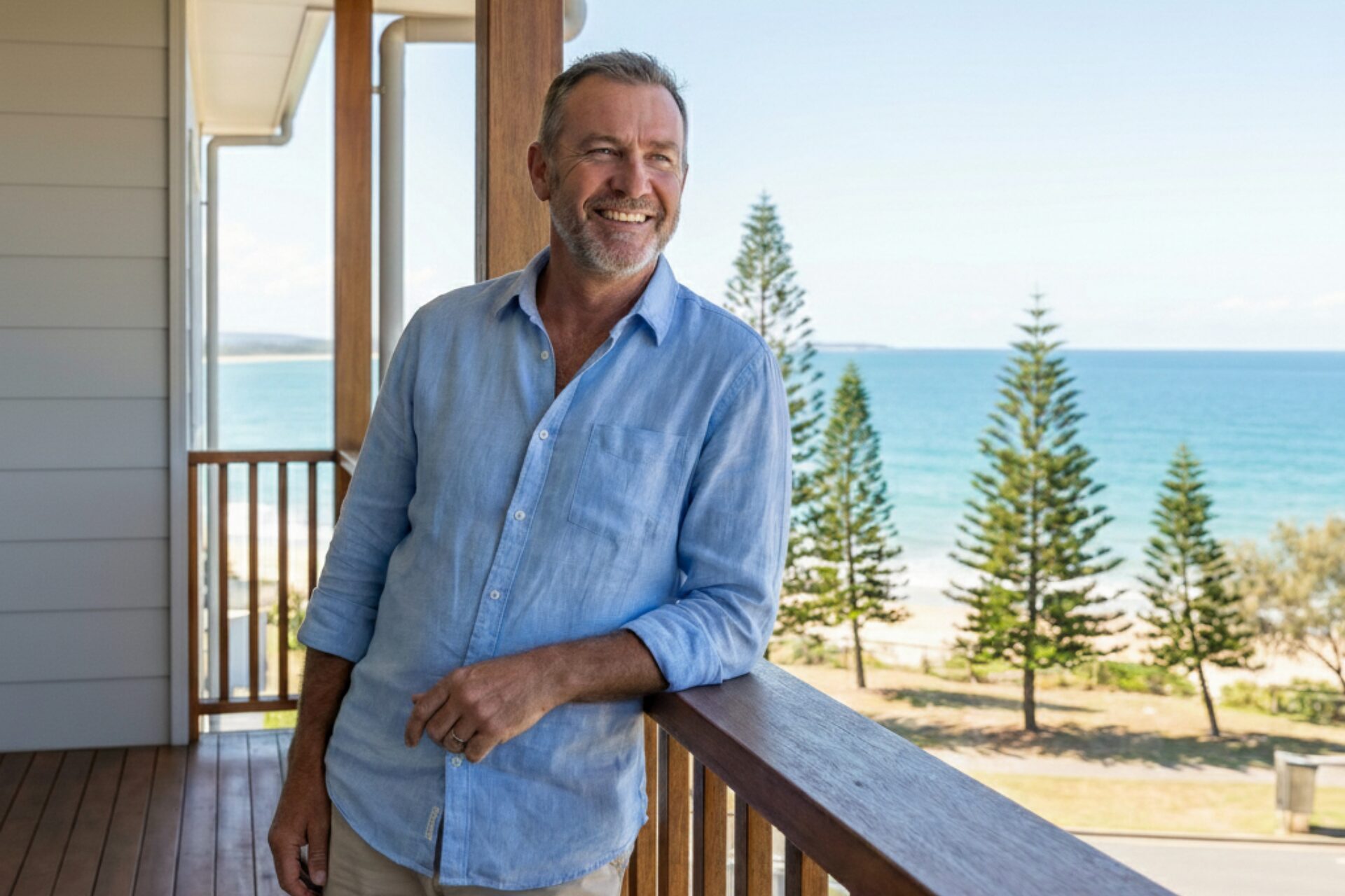 Man smiling on a beachside balcony view.